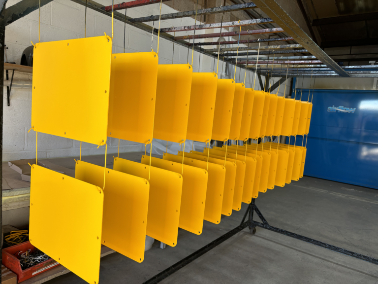 A production batch of yellow powder-coated metal panels at Halex