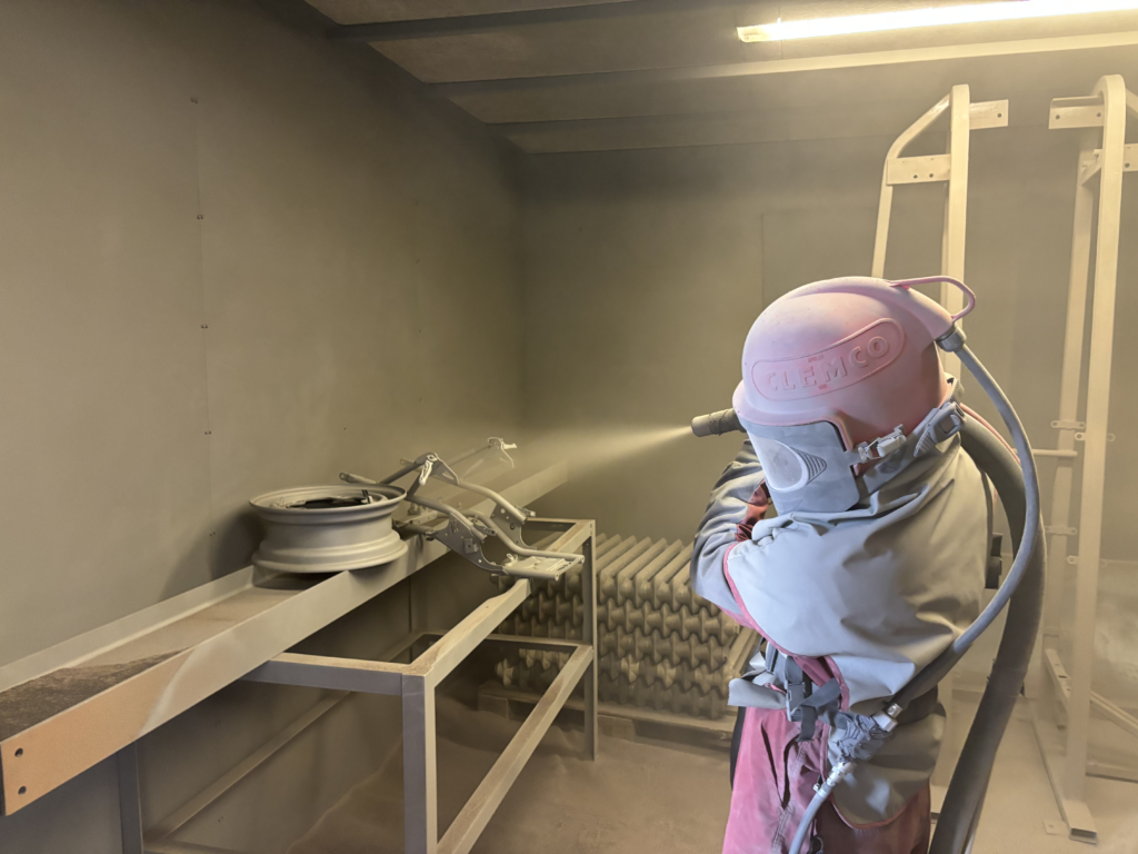An operator shot blasting metal components at Halex